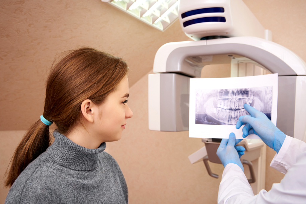 Dentist showing a young woman with red hair the results of her dental imaging.