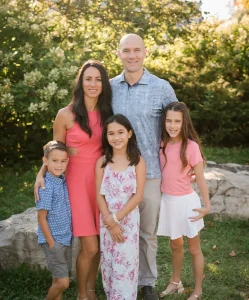 Family of five smiling together outdoors, representing community and family values associated with Paul DiFranco Orthodontics, a provider of braces and clear aligners in Palos Hills, IL.