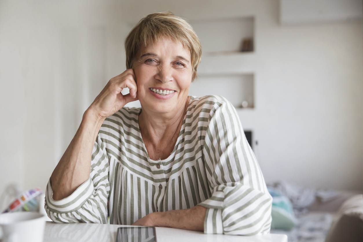 A late middle-aged lady wearing braces on her teeth and smiling broadly.
