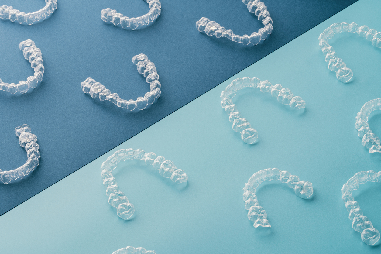Clear aligners arranged on blue and teal backgrounds, representing customized orthodontic treatment options at Paul DiFranco Orthodontics in Palos Hills, IL.